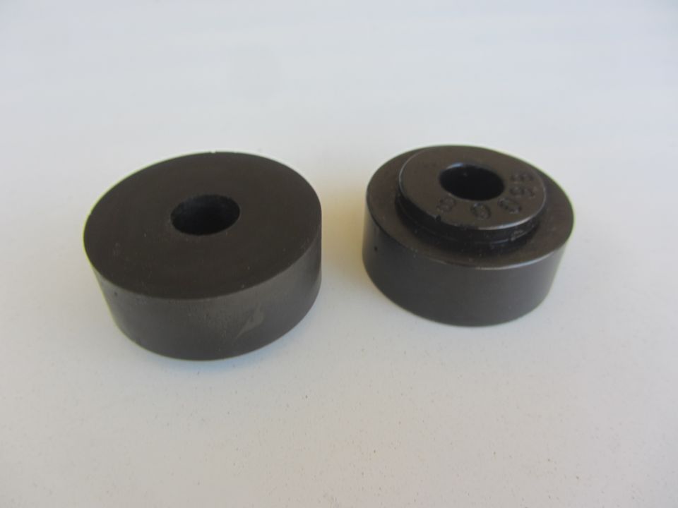 Two black rubber bushings, one with visible part number markings