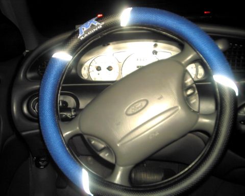 1997 Ford Taurus - The interior of a 1997 Ford Taurus is visible, a blue steering wheel cover and the Ford emblem on the steering wheel.