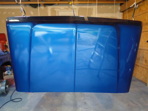1978 Ford Bronco - A freshly painted blue hood hangs from the ceiling in a garage, awaiting reinstallation.
