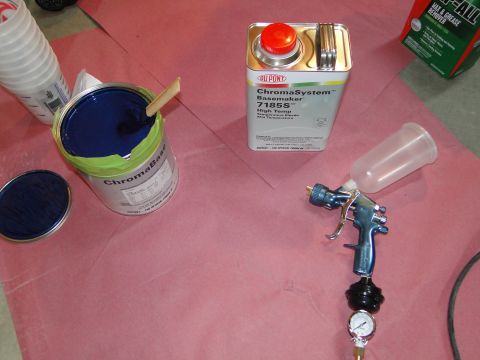 1978 Ford Bronco - Automotive paint supplies including a spray gun and solvent are laid out on pink paper.