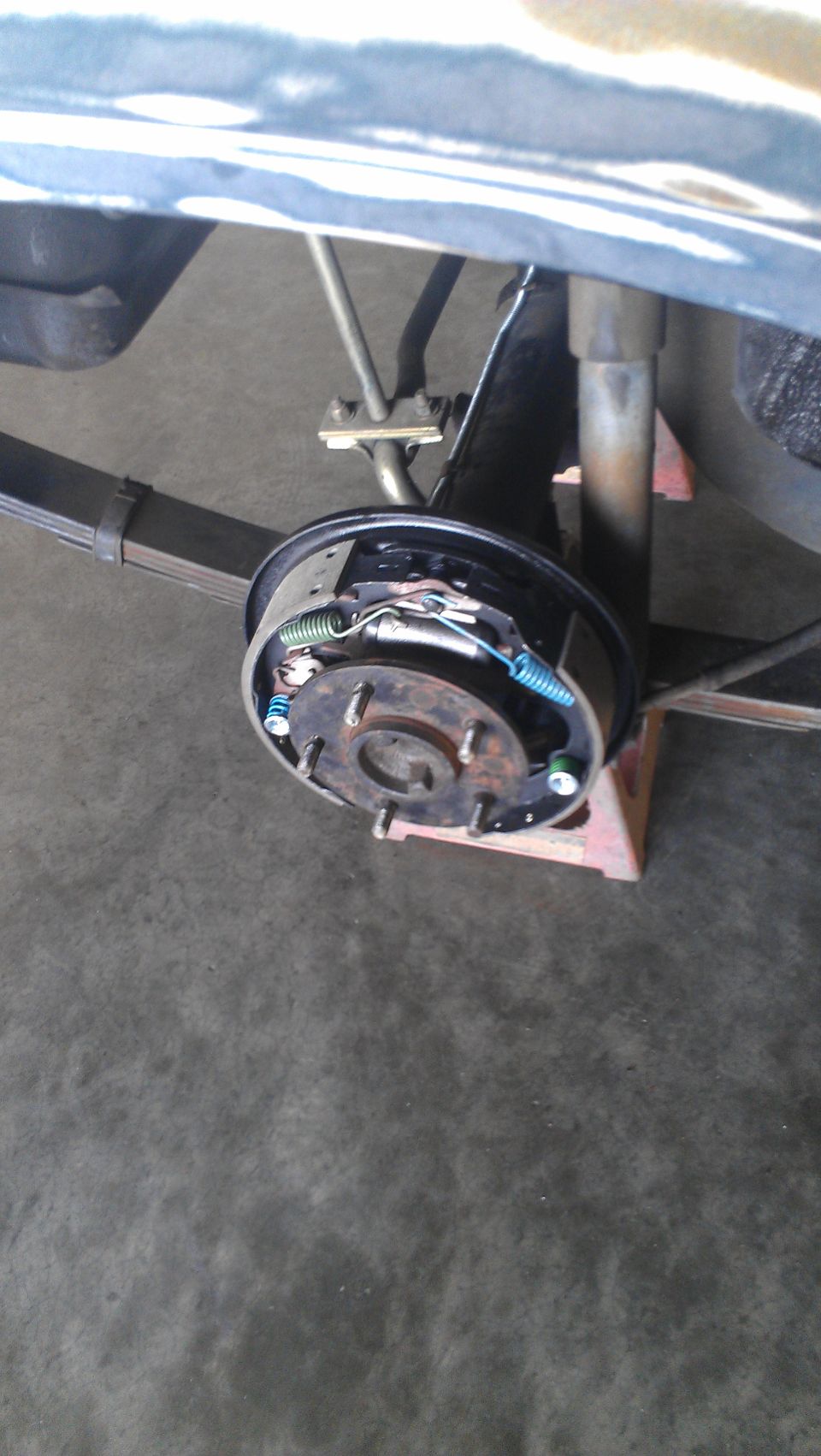 Close-up of a car's rear drum brake assembly with leaf springs and shock absorber visible