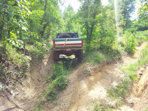 2012 Ford Bronco - This truck is navigating a steep, muddy incline surrounded by dense foliage.