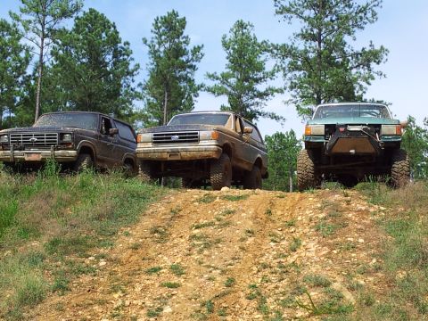 2012 Ford Bronco - Three Ford Bronco SUVs are positioned on a dirt incline, with two vehicles in the foreground and a third to the right.