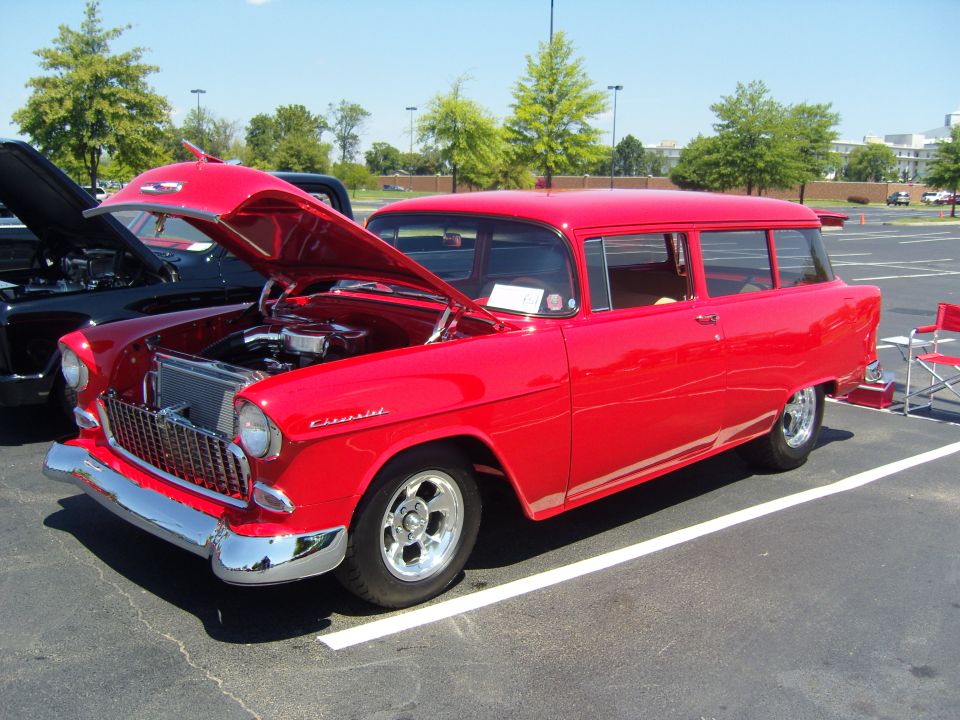 Red 1955 Chevrolet station wagon with hood open, parked next to a black car