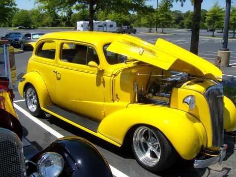 2007 Ford Mustang - A bright yellow vintage sedan is parked with its hood open, revealing the engine bay.