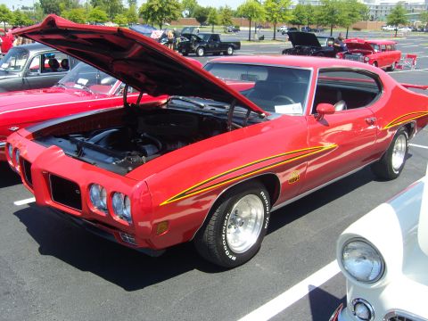 2007 Ford Mustang - A red 1970 Pontiac GTO is displayed with its hood open at an outdoor car show.