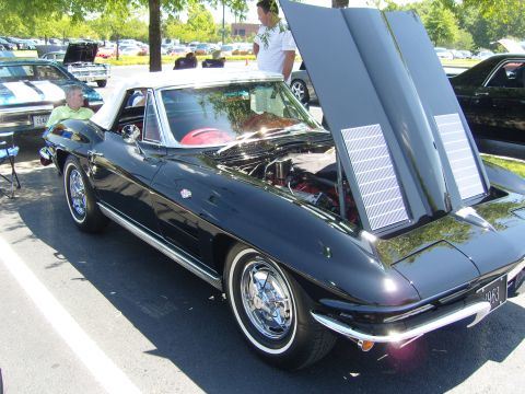 2007 Ford Mustang - A black 1963 Chevrolet Corvette Sting Ray convertible is displayed with its hood open at an outdoor car show.