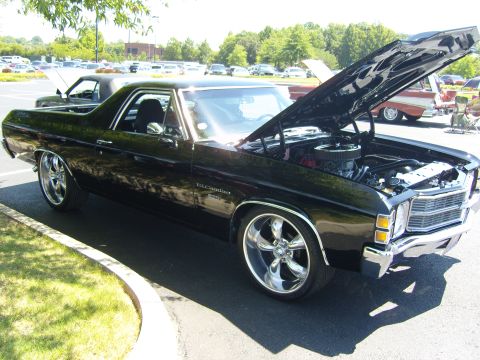 2007 Ford Mustang - A black El Camino is parked with its hood open, revealing the engine, and features chrome wheels.