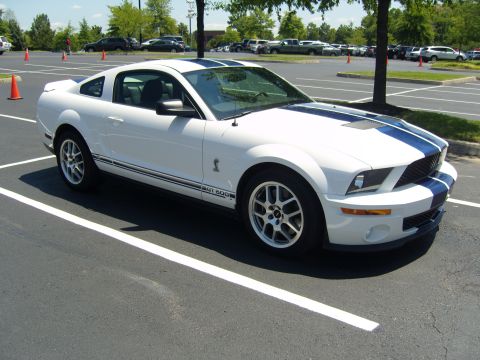 2007 Ford Mustang - White 2007 Ford Mustang GT500 with blue stripes in a parking lot.