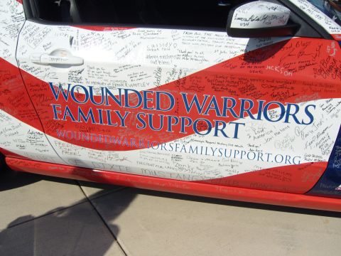 2007 Ford Mustang - A car door is covered in signatures and patriotic graphics, promoting 'Wounded Warriors Family Support'.