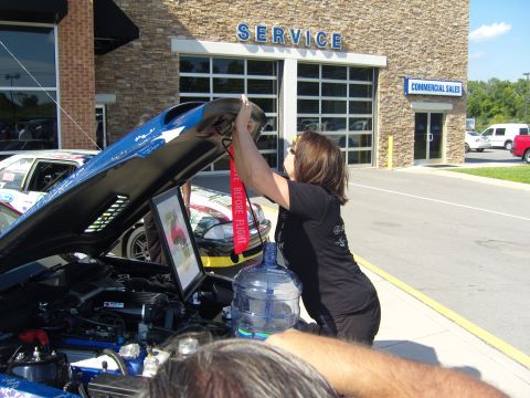 2007 Ford Mustang - Woman inspects the engine of a 2007 Ford Mustang during an event.