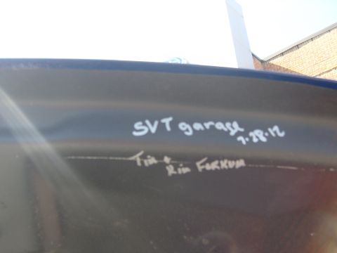 2007 Ford Mustang - Handwritten messages are visible on the dark surface of a vehicle's exterior panel.