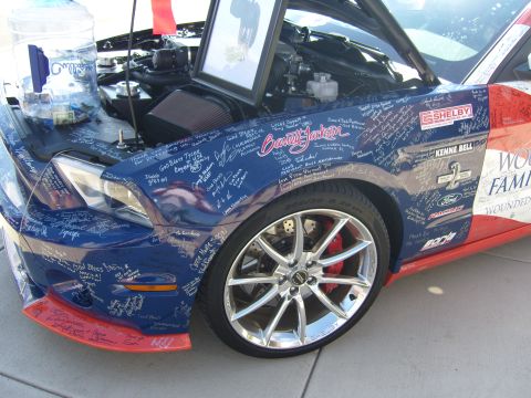 2007 Ford Mustang - A blue and red Ford Mustang is covered in signatures, with its hood open revealing the engine bay and a water cooler.