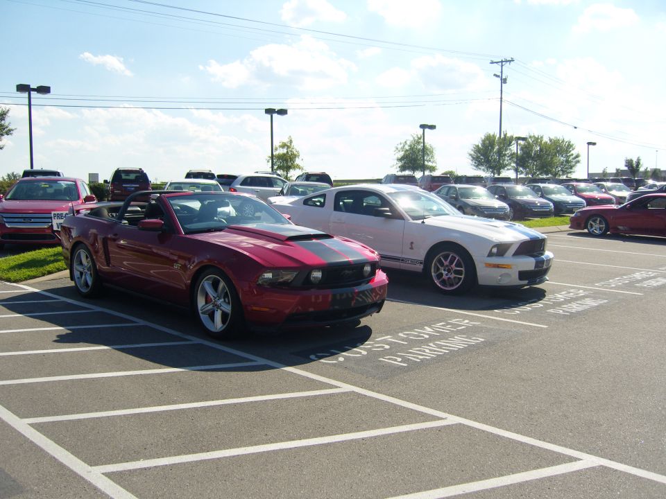Red convertible Ford Mustang with black racing stripes parked in a lot