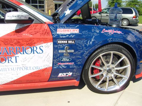 2007 Ford Mustang - This car is covered in signatures and decals, with the hood open, revealing more writing and stars.