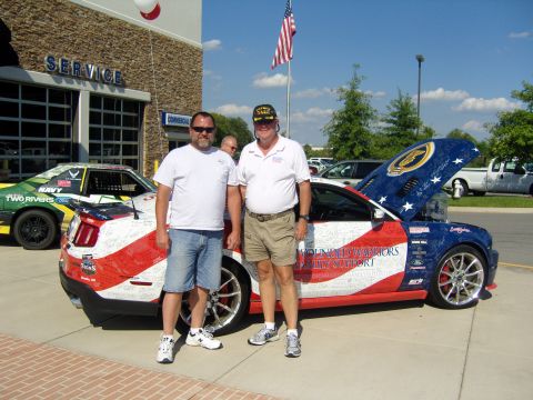 2007 Ford Mustang - Two men stand beside a custom Ford Mustang adorned with patriotic colors and signatures.
