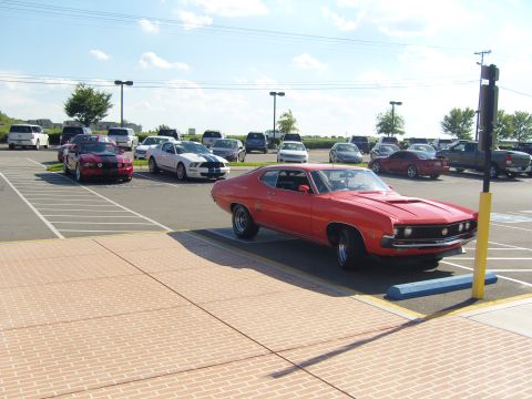 2007 Ford Mustang - A red vintage coupe is parked in a lot with several other vehicles visible in the background.