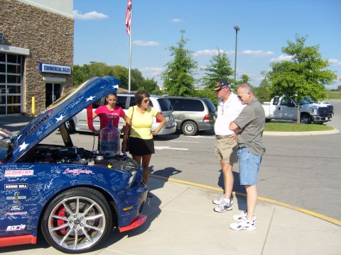 2007 Ford Mustang - A blue Ford Mustang with its hood open is displayed outdoors, with several people observing it.