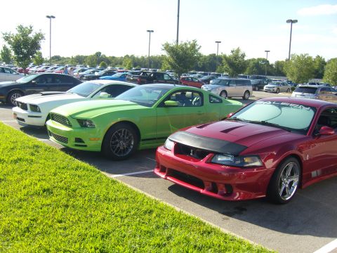 2007 Ford Mustang - Three Ford Mustangs are parked in a lot on a sunny day.