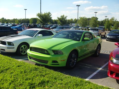 2007 Ford Mustang - Two Ford Mustangs are parked in a lot on a sunny day with a few clouds in the sky.