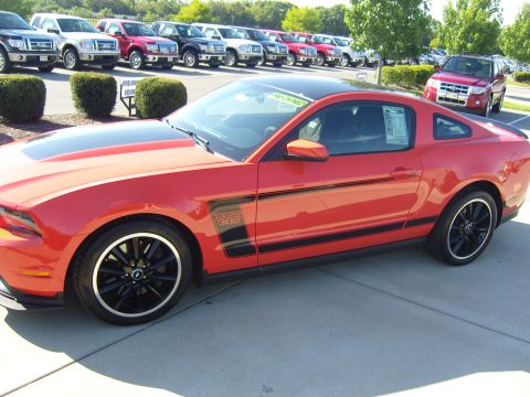 2007 Ford Mustang - Red Ford Mustang Boss 302 parked in a lot with other vehicles visible in the background.