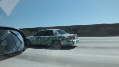 2003 Ford Crown Victoria - Panning shot of a green-and-black art-wrapped sedan blurring down the highway