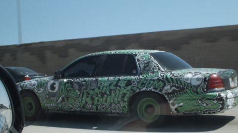 2003 Ford Crown Victoria - Profile of an art-wrapped full-size sedan showing detailed graffiti and green wheels