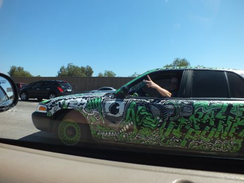 2003 Ford Crown Victoria - Close side shot of an art-wrapped sedan with the driver gesturing from the window