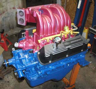 1988 Ford Bronco - Rebuilt Ford small-block V8 on an engine stand, painted Ford blue with a pink/red powder-coated EFI upper and lower intake manifold, yellow…