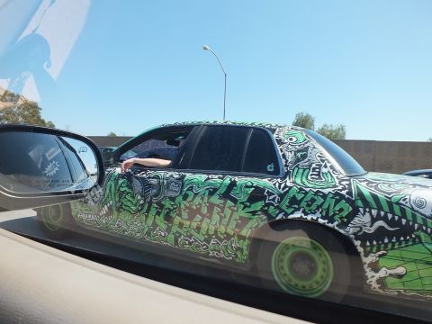 2003 Ford Crown Victoria - Tight side view of an art-wrapped sedan with green wheels passing in traffic
