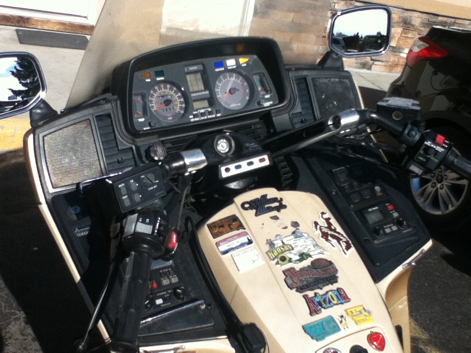 Motorcycle dashboard with gauges, controls, and various stickers on the fuel tank