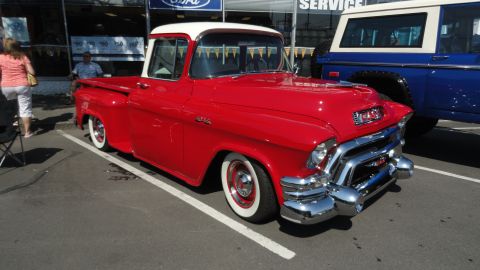 1964 Ford Fairlane - A classic red GMC pickup truck is parked next to a blue SUV.