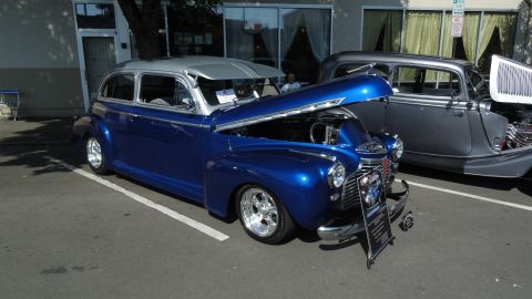 1964 Ford Fairlane - A blue 1941 Chevrolet Fleetline sedan is displayed with its hood open, parked beside another classic car.
