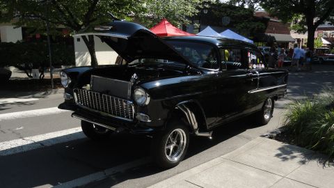 1964 Ford Fairlane - A classic black Chevrolet is displayed with its hood up on a sunny day.