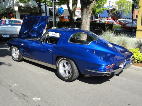 1964 Ford Fairlane - A shiny blue 1963 Corvette Stingray coupe is parked on a street with its hood open.