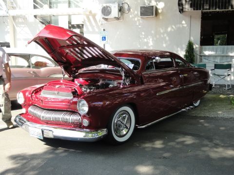 1964 Ford Fairlane - Customized 1950 Mercury coupe displays its engine, parked beside another classic car.