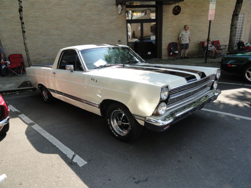 White Ford Ranchero with black racing stripes parked on asphalt