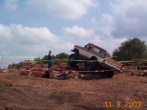 1992 Ford Bronco - A lifted Ford truck navigates a challenging off-road course with colorful marker ribbons.