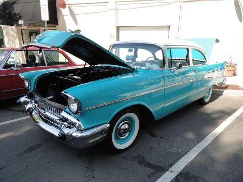 1964 Ford Fairlane - Turquoise 1957 Chevrolet Bel Air, hood and trunk open, parked beside a red vehicle.
