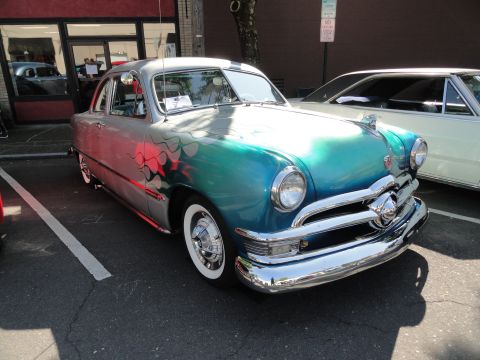 1964 Ford Fairlane - A customized classic car with a two-tone paint job and flame graphics is parked in a lot.