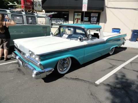 1964 Ford Fairlane - A classic turquoise and white pickup truck is parked next to a green van.