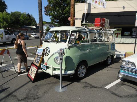 1964 Ford Fairlane - A Volkswagen Type 2 bus is parked on a street, displaying artwork and luggage on its roof.