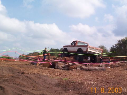1992 Ford Bronco - A lifted off-road truck navigates a course of logs, demonstrating its capabilities on challenging terrain.