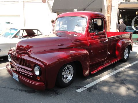 1964 Ford Fairlane - Customized red 1950s International Harvester L-series pickup truck parked next to a white car.