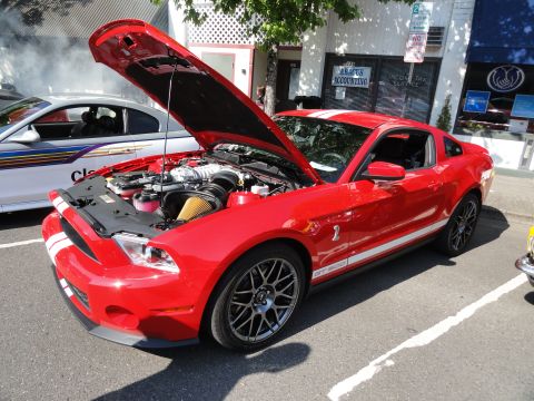 1964 Ford Fairlane - A red Ford Mustang Shelby GT500 is parked with its hood open, revealing the engine compartment.