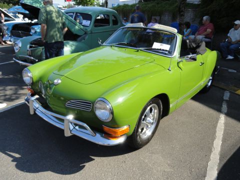 1964 Ford Fairlane - A bright green convertible is parked next to a green sedan at an outdoor car show.