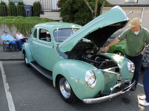 1964 Ford Fairlane - A man inspects the engine of a mint green 1940 Ford coupe at an outdoor gathering.