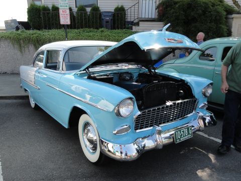 1964 Ford Fairlane - A light blue 1955 Chevrolet Bel Air is parked with its hood open, showing the engine bay.