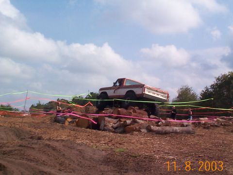 1992 Ford Bronco - A lifted truck navigates a challenging obstacle course made of logs and dirt.