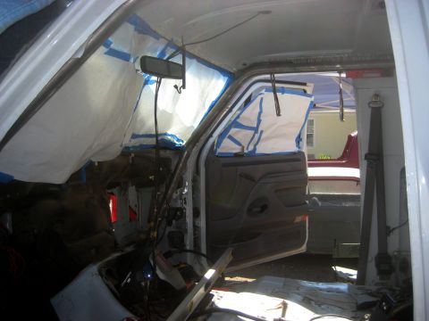 1996 Ford Bronco - The interior of a vehicle is being worked on, with windows covered and a roll cage visible.